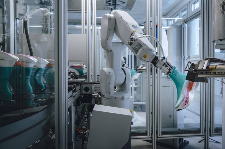 Der Roboter sprüht den Schuh auf den Leisten (in Türkis).