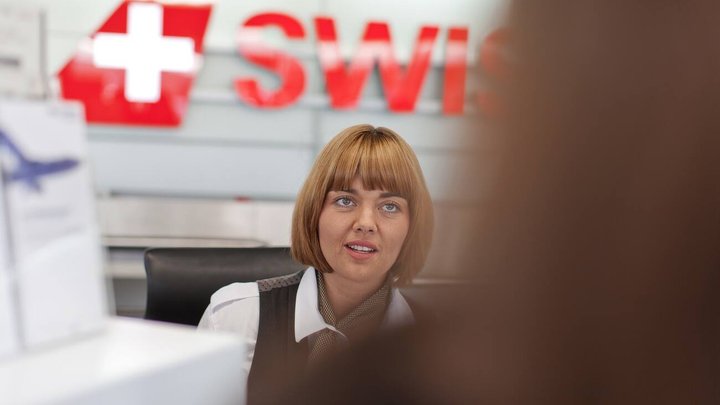 Eine Mitarbeiterin der Fluggesellschaft swiss bedient eine Kundin am Check in in der Halle 1 am Flughafen in Zuerich, aufgenommen am 7. August 2012. (KEYSTONE/Gaetan Bally) [GESTELLTE AUFNAHME]