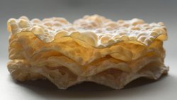 Die Blasen erhält der Teig durch das Ausrollen mit einem Nadelholz vor dem Frittieren.