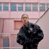 GUCCI Oversize-Lederblouson aus Pythonleder mit grosser Strassbrosche, Minirock, beige Seidenbluse mit Spitzenkragen, Tasche Jackie 1961.
