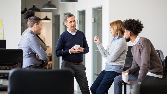 Fünf Personen unterschiedlichen Alters diskutieren miteinander im Büro.