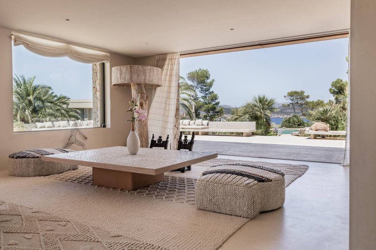 Blick aus dem Wohnzimmer mit grossen Fenstern und weit öffnenden Terrassentüren.