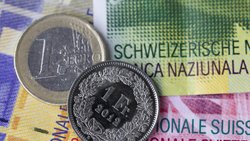 Euro- und Frankenmünze auf Schweizer Banknoten.