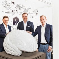 Brainees: Pascal Kaufmann, Oliver Muhr und Marc Vontobel (v.l.) vor einem stilisierten Gehirn, dem Markenzeichen von Starmind.