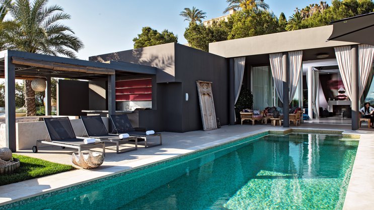 Aus dem grosszügigen Living Room führt der Weg zum Poolbereich mit Blick auf Ibiza-Stadt und aufs offene Meer. Die früher grellweiss gestrichenen Wände hüllte Anja Graf in dunkle Töne.