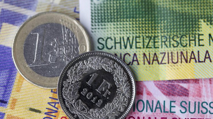 Euro- und Frankenmünze auf Schweizer Banknoten.