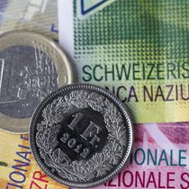 Euro- und Frankenmünze auf Schweizer Banknoten.