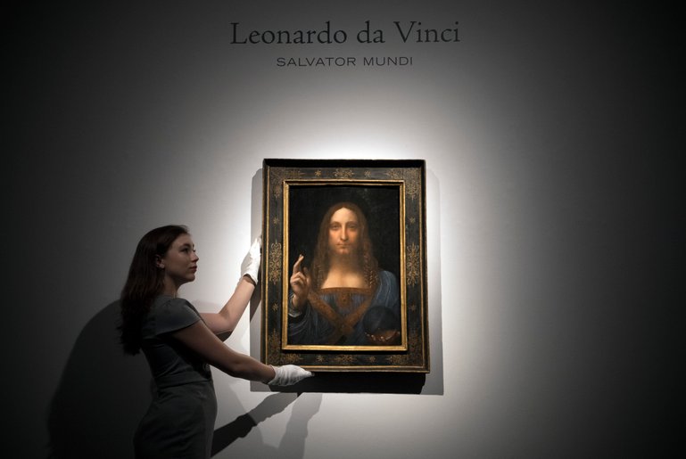 LONDON, ENGLAND - OCTOBER 24:  A member of staff poses with a painting by Leonardo da Vinci entitled 'Salvator Mundi' before it is auctioned in New York on November 15, at Christies on October 24, 2017 in London, England. The painting is the last Da Vinci in private hands and is expected to fetch around 100,000,000 USD.  (Photo by Carl Court/Getty Images)