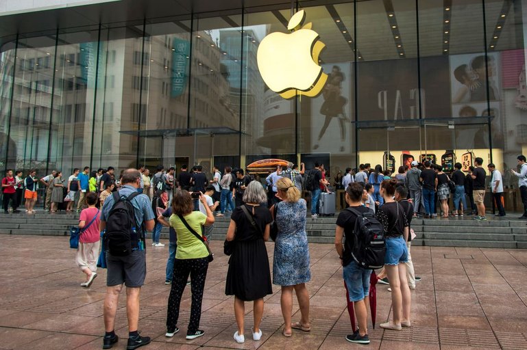 In this Friday, Sept. 21, 2018, photo, foreign tourists watch people queue in line to enter the Apple Store for the debut of the latest iPhones in Shanghai. China imposed new tariff hikes on U.S. goods on Monday, Sept. 24, 2018, and accused Washington of bullying, giving no sign of compromise in an intensifying battle over technology that is weighing on global economic growth. (Chinatopix via AP) (KEYSTONE/AP CHINATOPIX/)